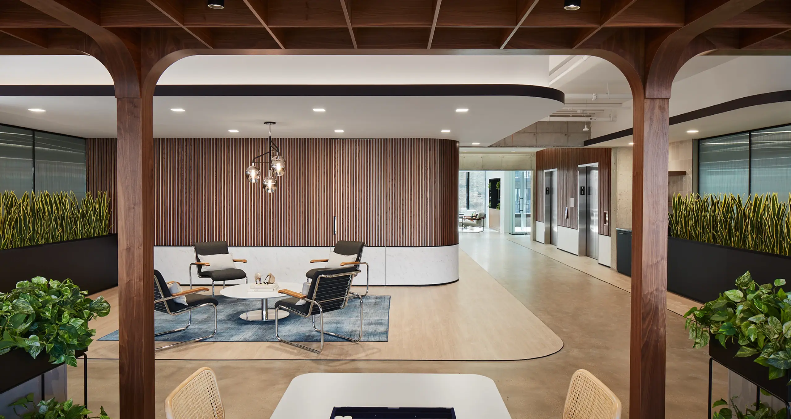 Corporate lobby lounge with natural wood design, stylish lighting, and mid-century modern furniture
