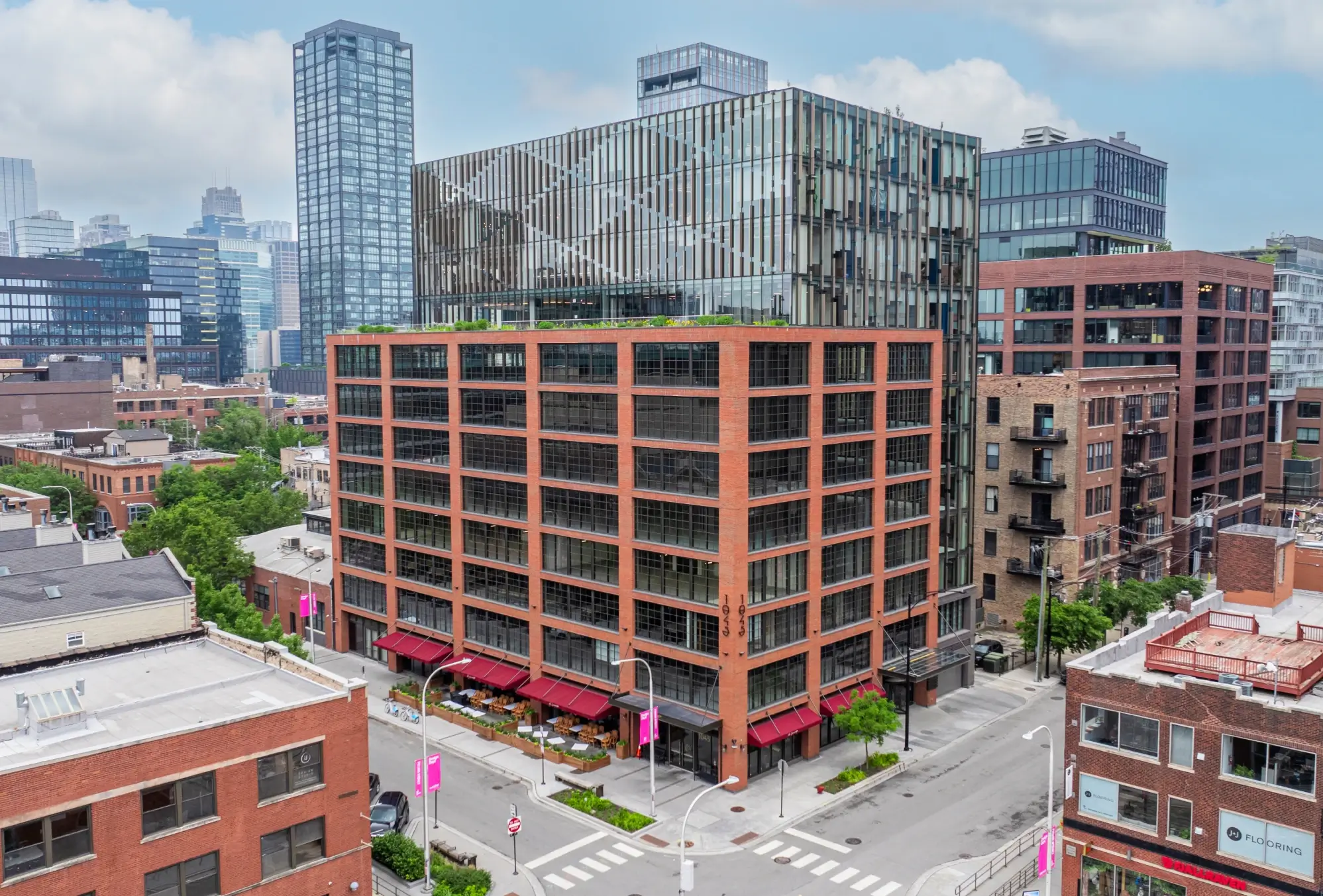 Aerial view of modern red-brick building in urban district with glass office tower above