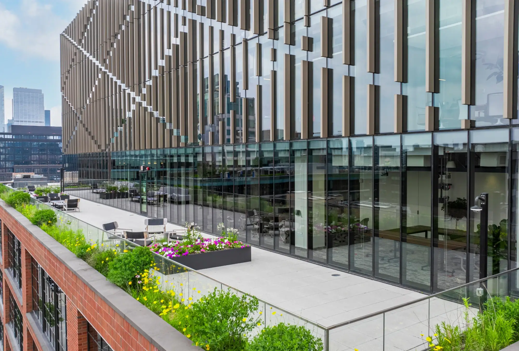 Rooftop terrace featuring lounge furniture, glass railing, and reflective modern office facade