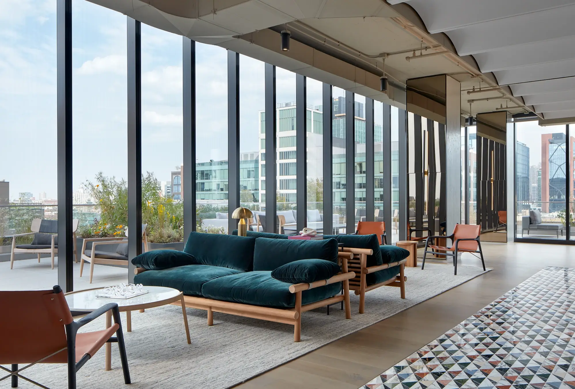 Interior lounge space with velvet sofas, floor-to-ceiling windows, and outdoor patio views.