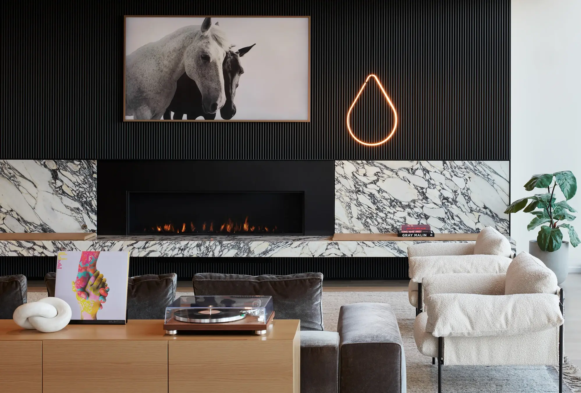 Cozy fireplace lounge with marble walls, modern art, and soft neutral-toned seating