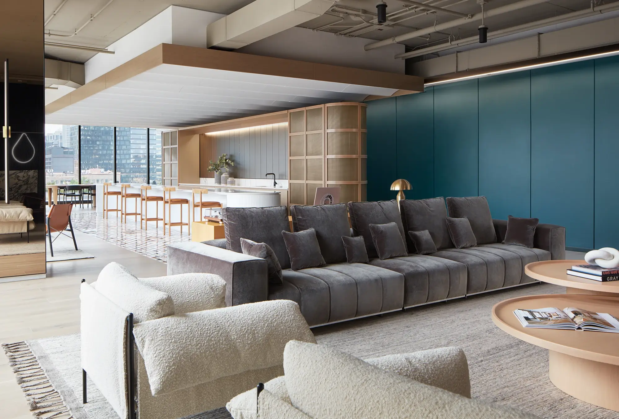 Sophisticated open kitchen with curved white island, high-back chairs, and lounge with charcoal sectional