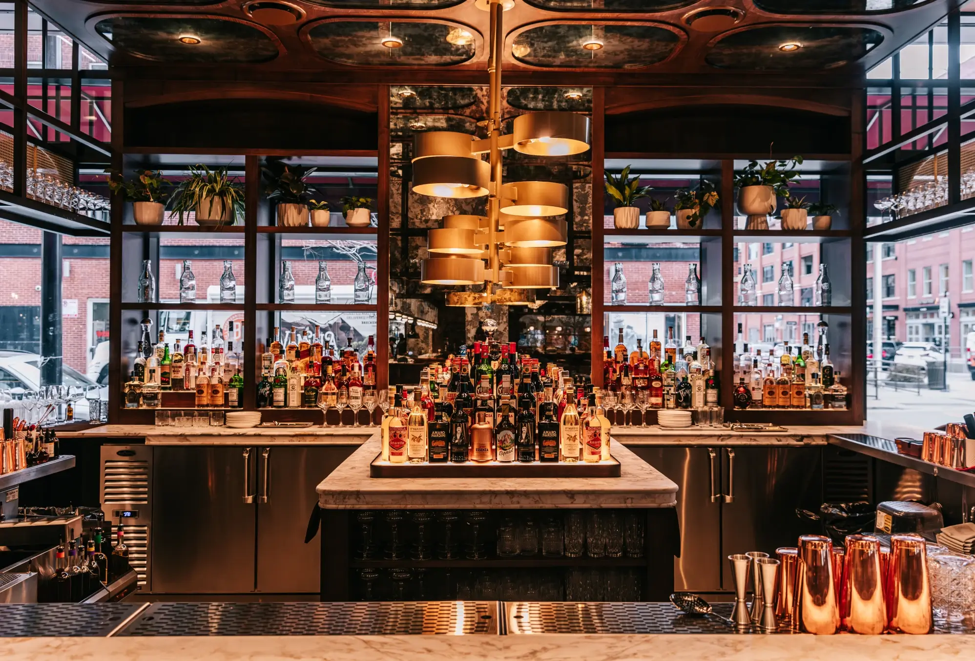 Elegant bar interior with shelves of liquor bottles, gold lighting, and mirrored back wall.