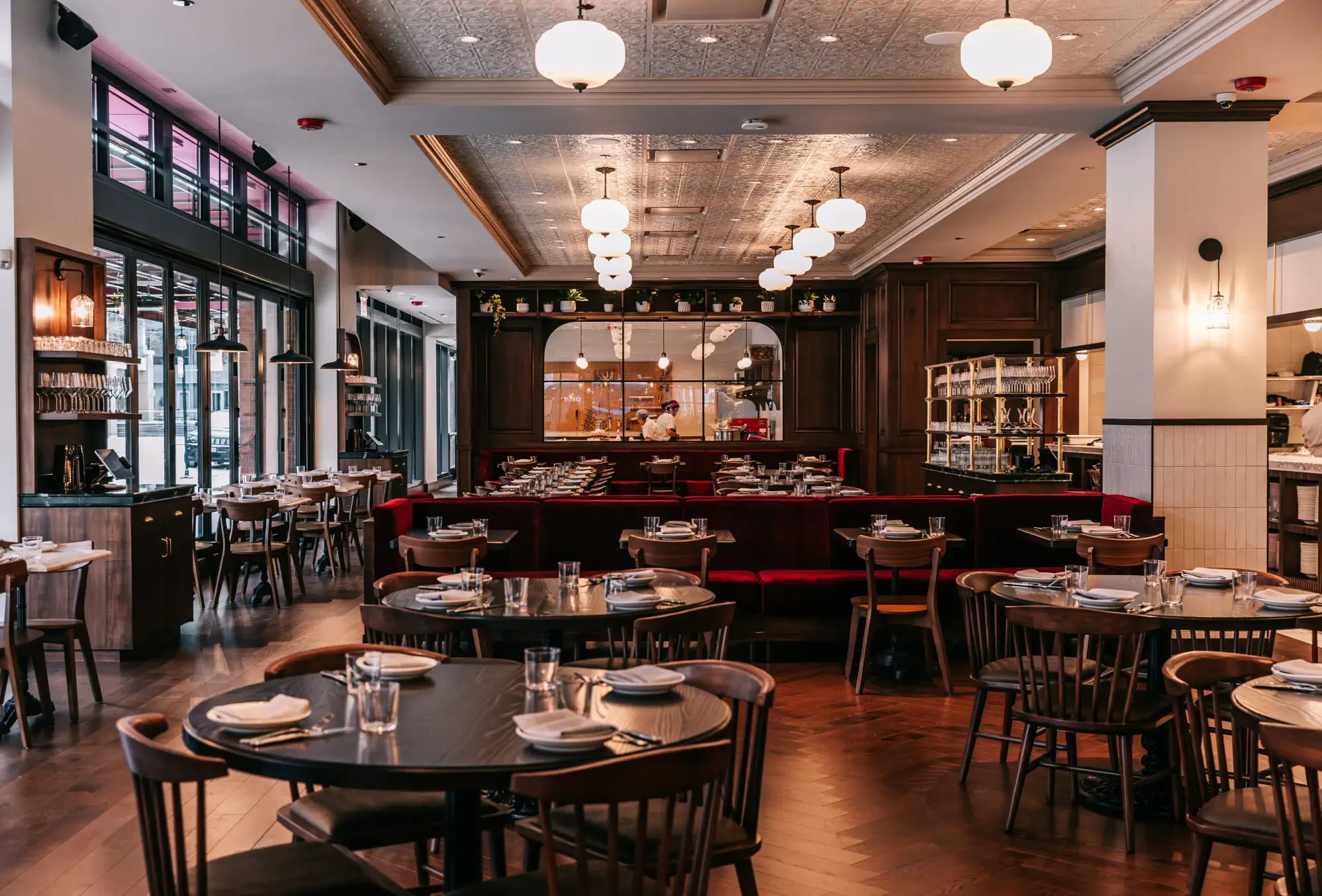 Classy restaurant dining room with wood tables, red booths, and warm pendant lighting.