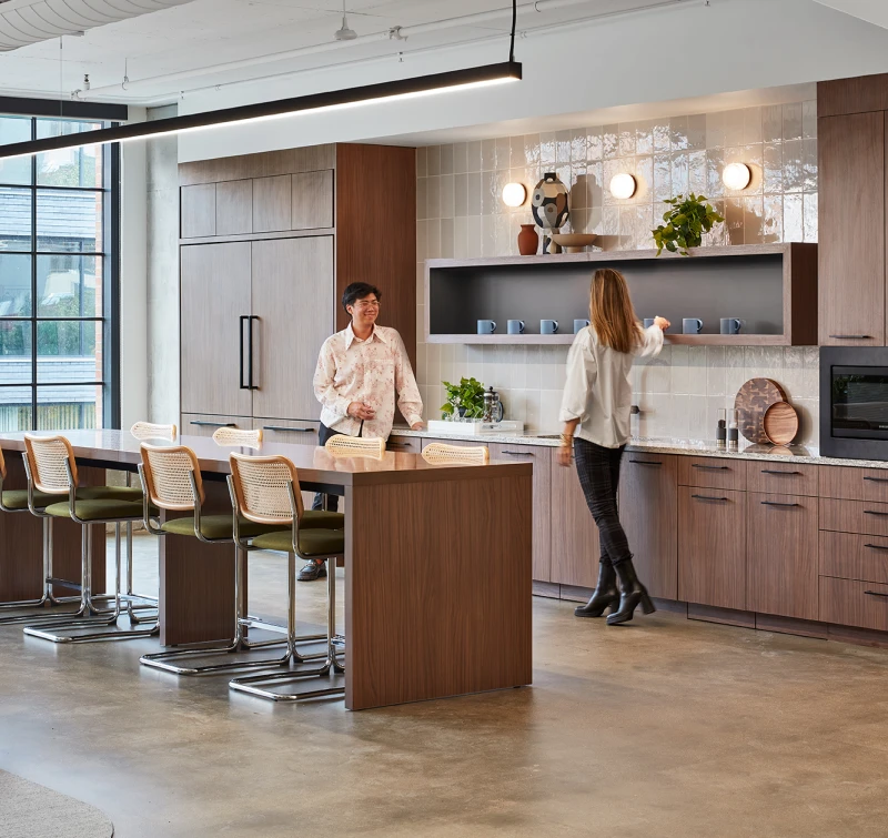 Wellness-focused workplace kitchen featuring wood cabinetry, bar seating, and natural lighting.